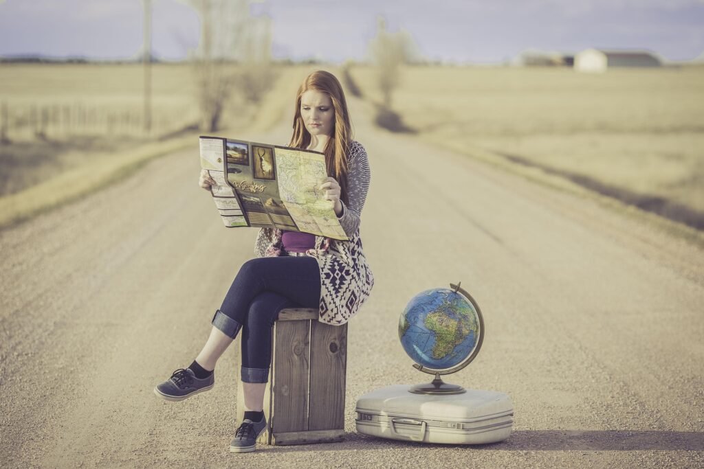 Travel Adventure: Discover New Destinations and Explore the World Travel enthusiast exploring a scenic destination with a map, globe, and suitcase on an open road.